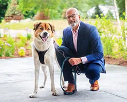 A person kneeling down next to a dog outside