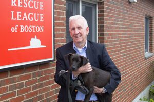 A man holding a small puppy outside a brick building