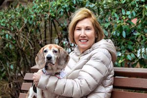 A women sitting with a Beagle dog on a bench outside