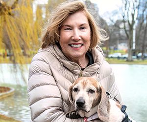 A woman outside sitting, holding a beagle dog